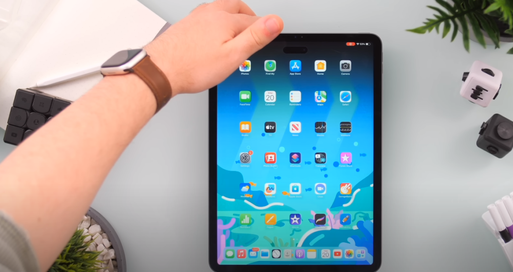 Hand with watch holding iPad Pro in portrait orientation