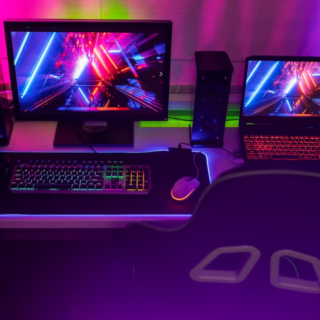 computer and laptop on the desk with colorful neon pictures